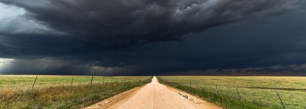 Donker wolken in een weiland boven een weg