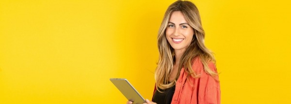 Blonde vrouw met tablet in de hand op een gele achtergrond