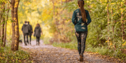 Vrouw loopt in een bos met een groepje mens met hond voor haar uit
