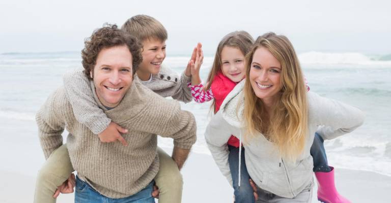 Gezin op het strand ouders met kinderen op hun rug