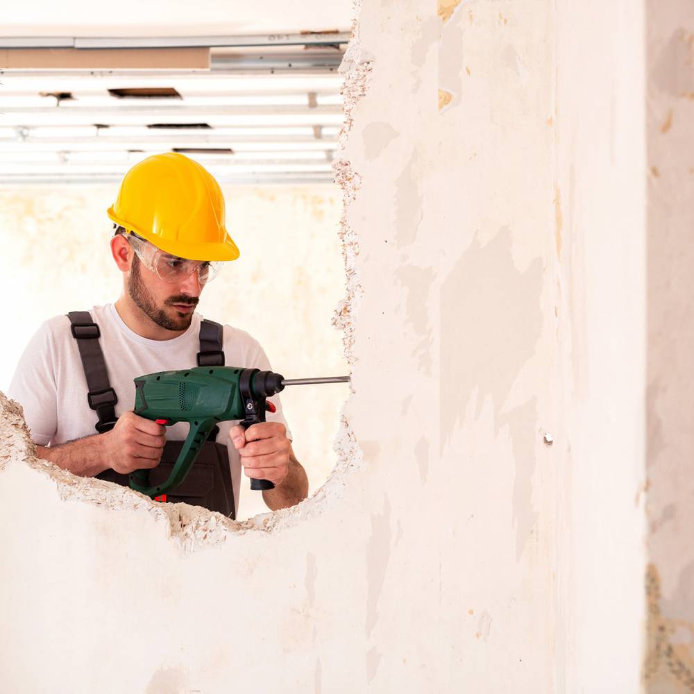 klusjesman, verbouwing, gaten in de muur, klussen, man, verzekeringen, schade zakelijk, gele beschermingshelm