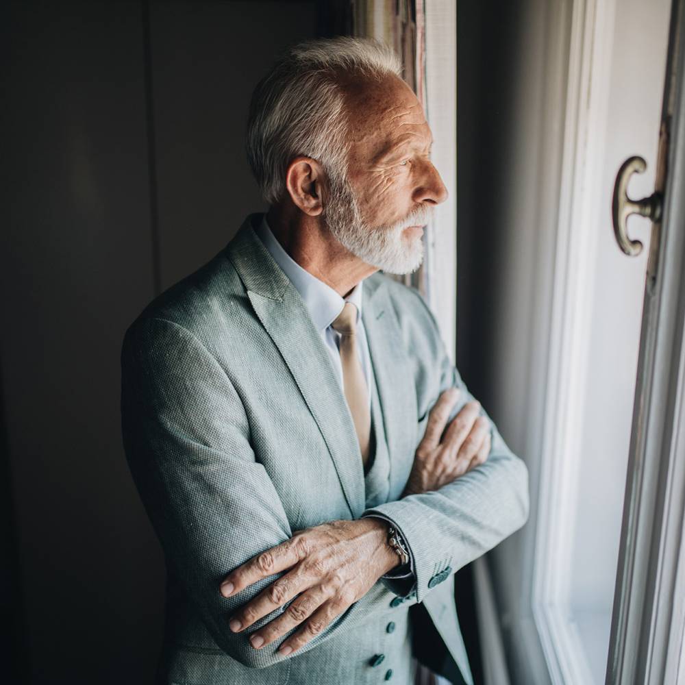 Bezorgd zakenman op zoek door het raam van een appartement