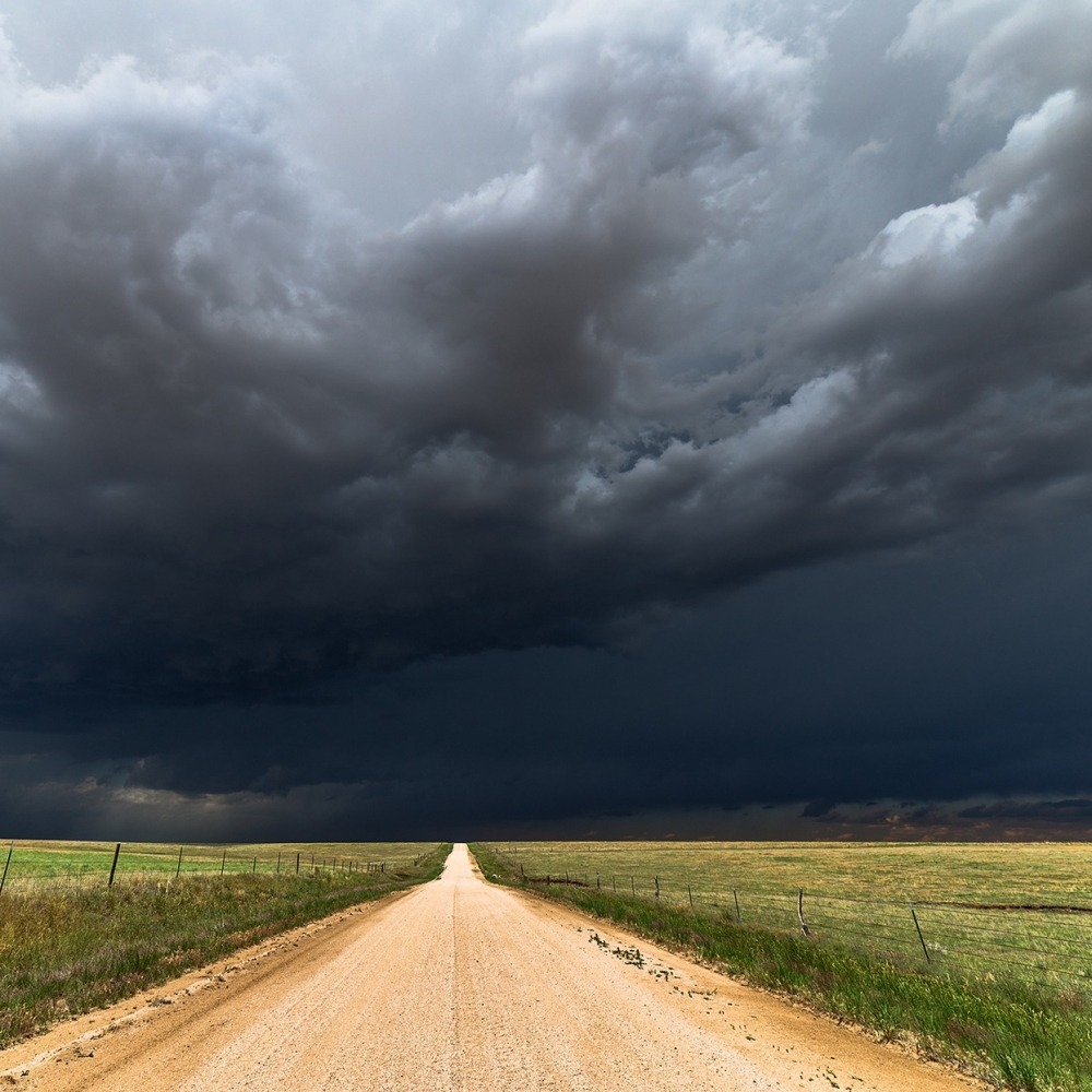 Donker wolken in een weiland boven een weg